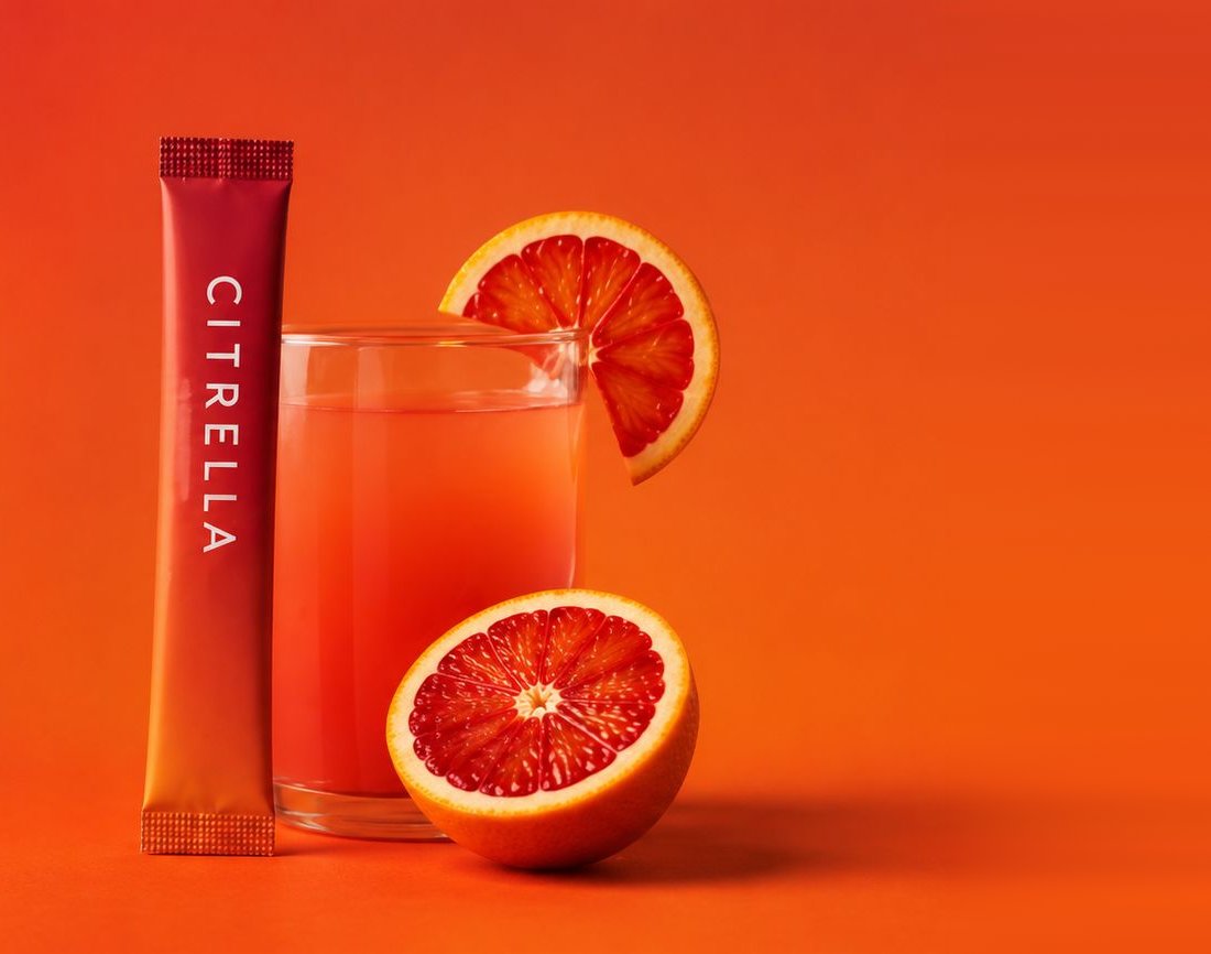 Slim stick Citrella dressé à côté d’un verre de boisson à l’orange sanguine et de deux moitiés d’orange