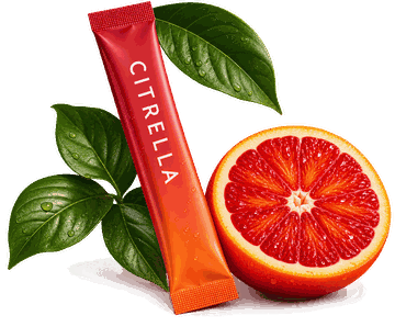 Stick Citrella posé contre une demi orange sanguine et des feuilles vertes